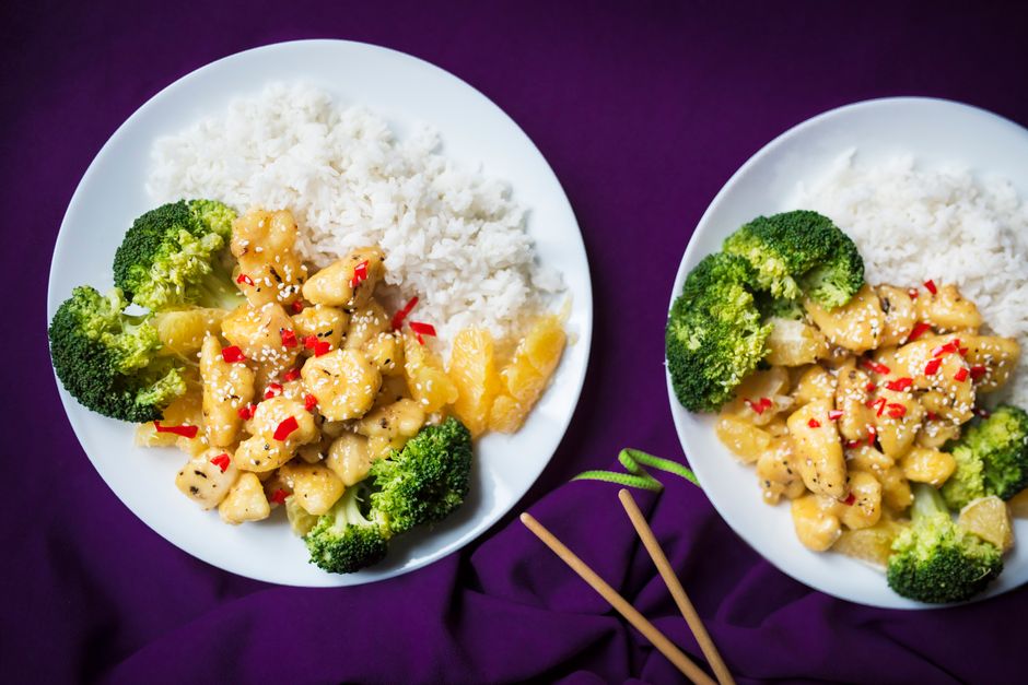 Top view of Asian chicken stir fry with rice and broccoli on a white plate.
